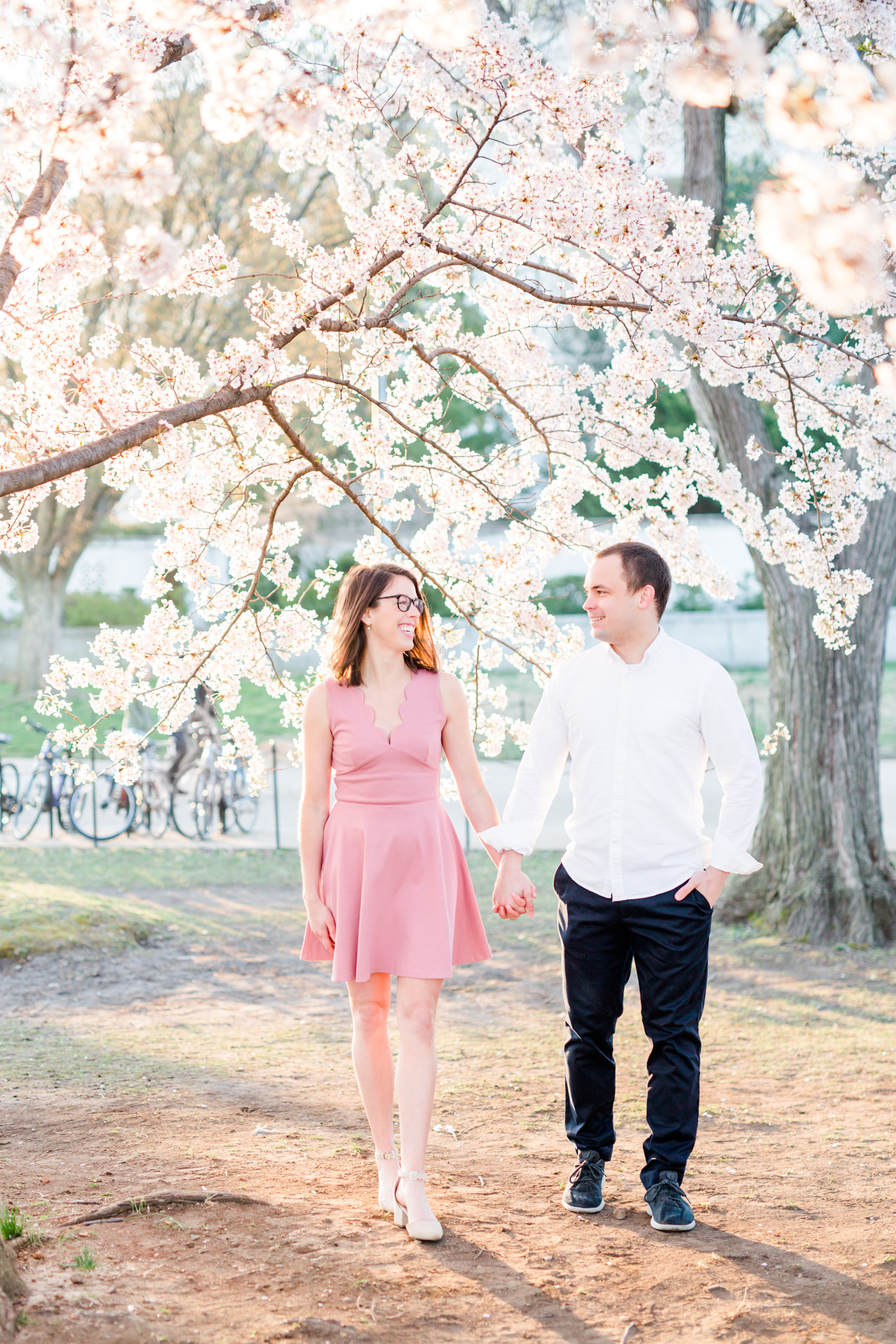 sunny cherry blossoms engagement session, Washington, D.C. engagement photos, Washington D.C. engagement photos, sunrrise engagement photos, cherry blossom engagement photos, D.C. cherry bloossoms, D.C. cherry blossoms photos, cherry blossom photos, cherry blossoms portrraits, sunny engagement photos, classic engagement photos, Rachel E.H. Photography, engagement session style, couple holding hands, couple walking