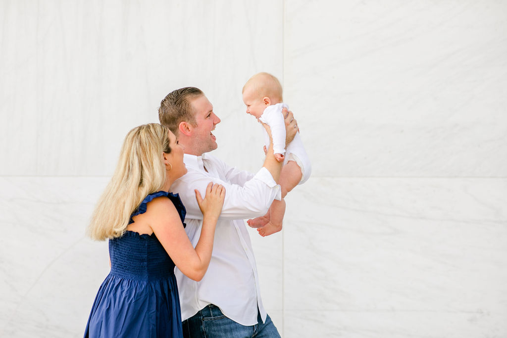 Kennedy Center family portraits, DC family portraits, classic DC family photos, casual family portraits, spring family portraits, Kennedy Center portraits, family of three, couple with baby, Rachel E.H. Photography, man holding baby up, baby laughing, mom looking at baby