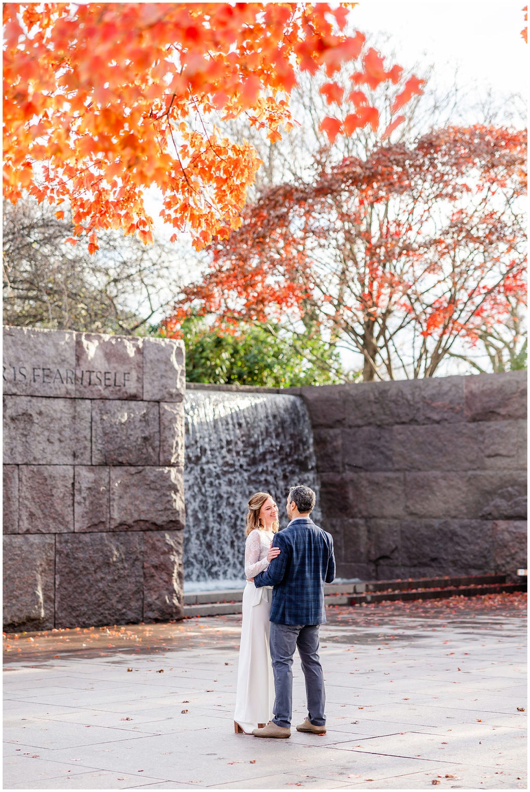 FDR Memorial elopement, DC War Memorial elopement, DC War Memorial photos, DC War Memorial wedding, DC portraits, tidal basin portraits, DC wedding photography, DC elopement photographer, cold weather elopement, Rachel E.H. Photography, couple smiling at each other, couple laughing, couple in front of waterfall, orange and red leaves