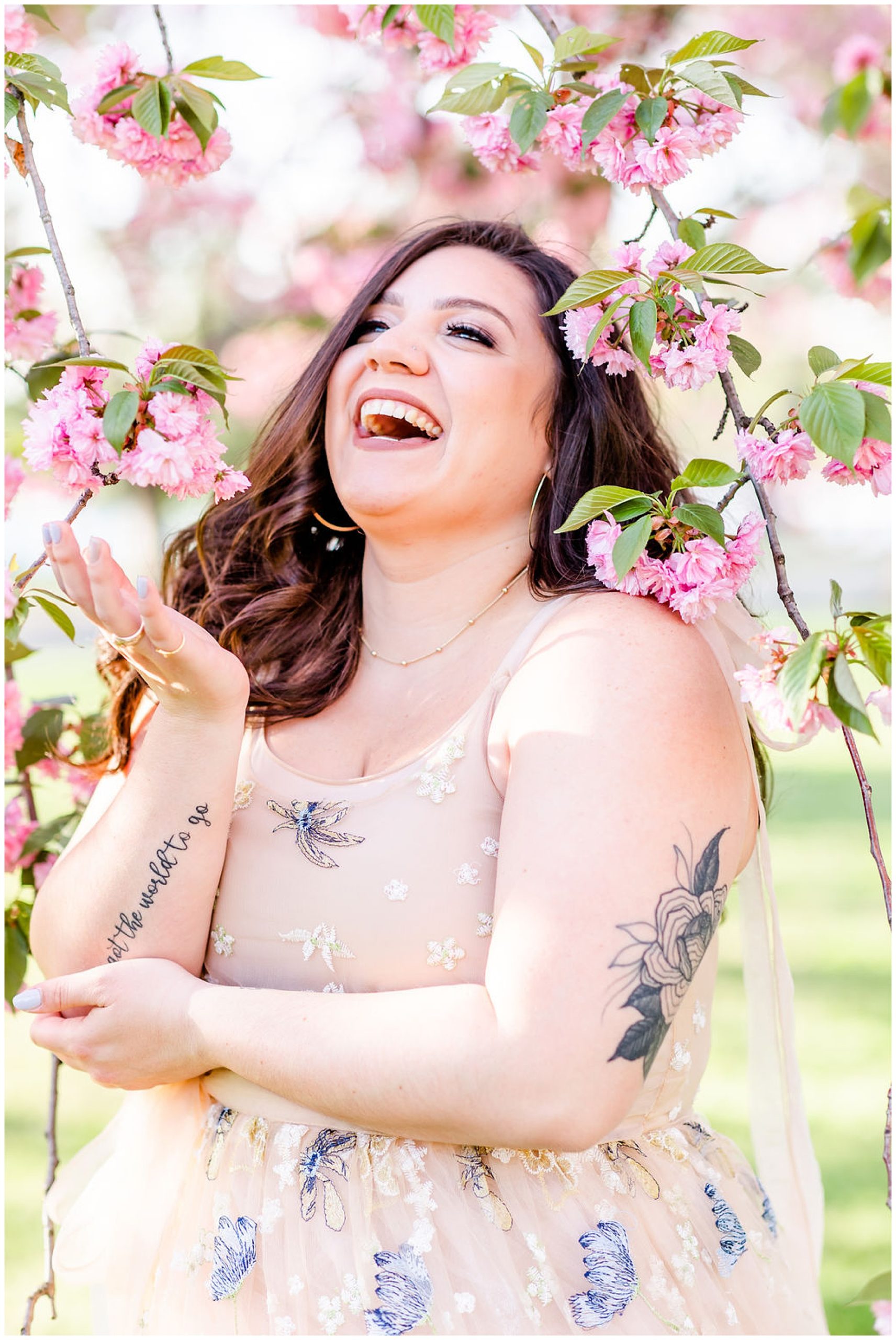 kwanzan cherry blossoms ballgown photos, cherry blossom portraits, kwanzan cherry blossom portraits, D.C. cherry blossoms, spring portriats, just because photos, just because portraits, cherry blossom headshots, Rachel E.H. Photography, woman laughing, woman with tattoos, woman reaching out for cherry blossom flower