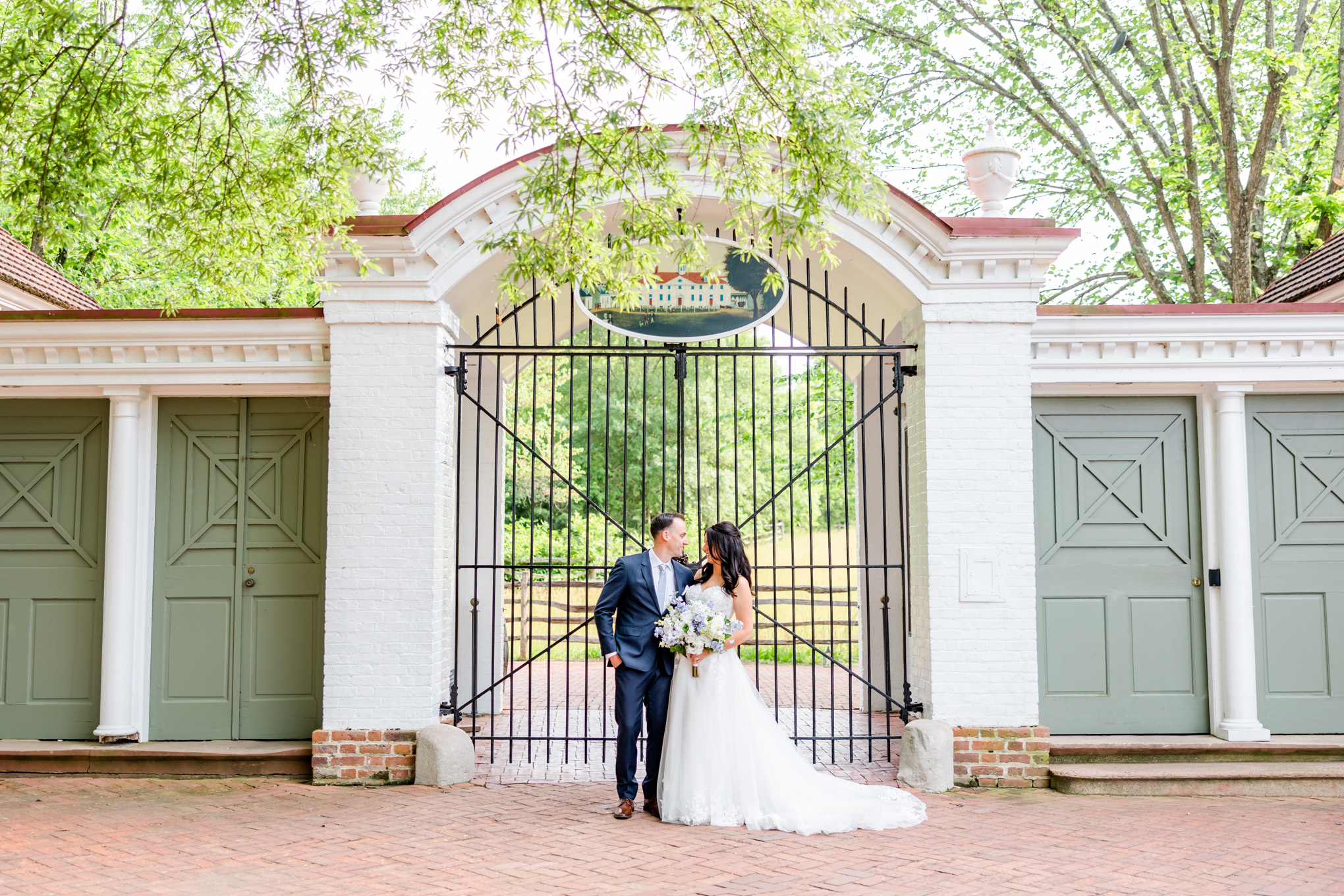 dreamy spring Mt. Vernon Inn wedding, Mount Vernon Inn Restaurant, Mount Vernon Virginia, classic D.C. wedding, classic spring wedding, white and blue wedding, steel blue aesthetic, spring wedding, spring wedding aesthetic, Rachel E.H. Photography, D.C. wedding photography, D.C. wedding photographer, couple smiling at each other, tall iron gate, bride and groom smiling, Generation Tux